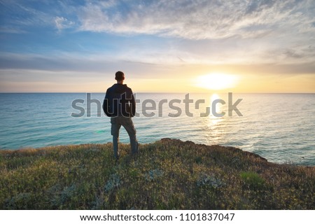 Man stands on the edge of the abyss and looks at the sea. Man relax on nature.  Royalty-Free Stock Photo #1101837047