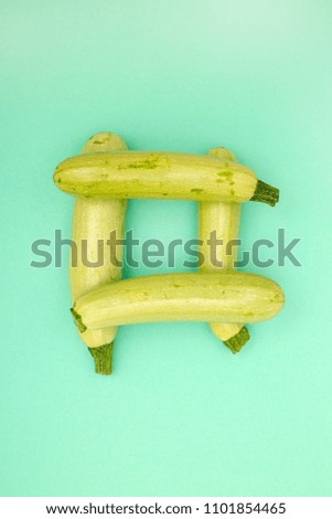 Four ripe zucchini stacked on a green background