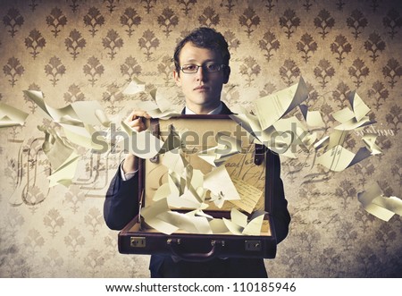 Young businessman holding an open briefcase with paper sheets flying away from it