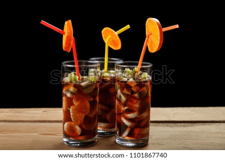 glasses with a fruit cocktail are on a wooden table on a black background. Front view, close-up