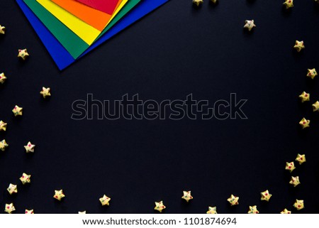 colored paper on black background. Neat sheets of papers and folded paper star. blank for text and design.
