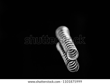 Silver metal spring isolated on black background with reflection. Macro photography