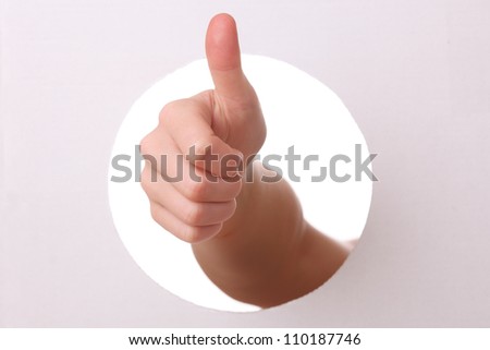 Arm reaches trough a hole with thumbs up