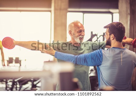 Fitness instructor helping senior man  in exercise.