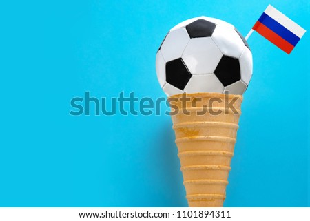  Ice cream cone and a soccer ball on a pastel blue background. Minimal summer concept.