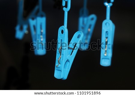 Hanging blue clothespin on black background