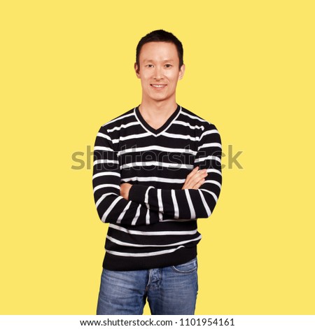 Asian man in striped pullovert, looking on camera, with folded hands, isolated on trendy gradient background