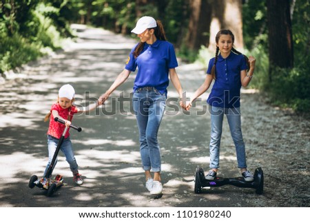 Mother with daughters in park on segway and skate