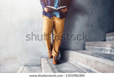 Lower Part of Person Standing and Reading Book at Outdoor Stair in Summer Sunny Day