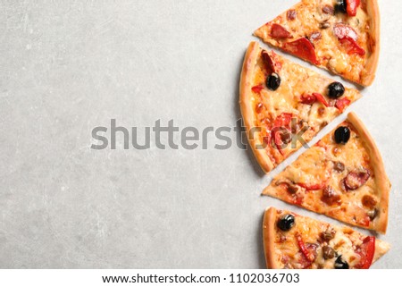 Slices of tasty pizza with olives and sausages on gray table