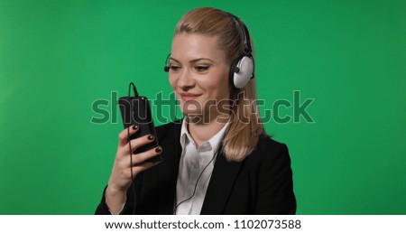 Happy Business Woman Laughing while Watch a Movie on Mobile Phone Using Headphones with Green Screen Background