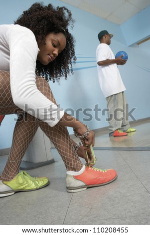 Young african american woman putting on bowling shoes