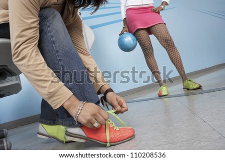 Young woman putting on bowling shoes