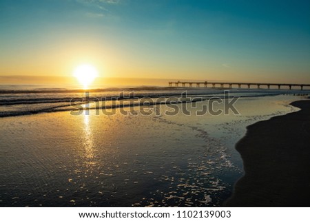 Sunrise over beach in Jacksonville. Pier in the background. Florida, USA.