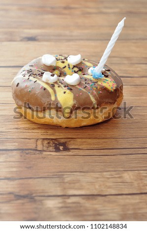 A colorful doughnut with a white birthday candle
