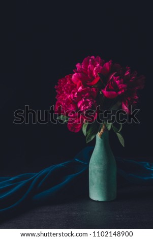 bouquet of pink peonies in vase on dark background