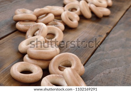 A lot of fresh yellow bagels lie on the surface of the old dark wood. A popular kind of flour products. One of the traditional Russian treats for tea
