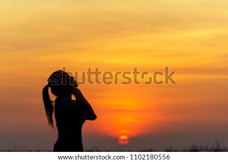 Silhouette women runner listening music and feeling freedom, happy and enjoying nature sunset.  Lifestyle and Healthy Concept.
