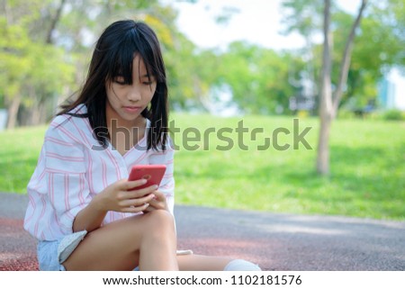 Asian girl using a smartphone in the flower garden
