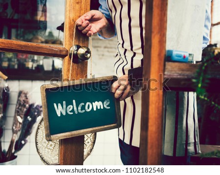 Welcome sign hanging on a glass door