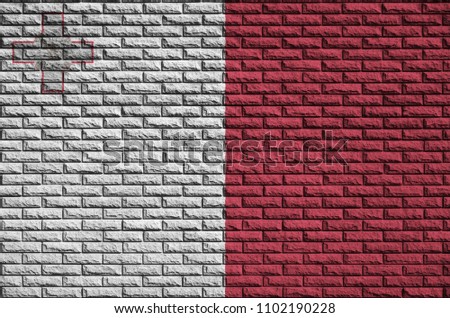 Malta flag is painted onto an old brick wall