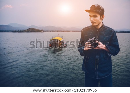 Hand holding camera dslr to travel at river sunset,Holiday travel vintage