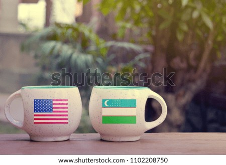 United State of America and Uzbekistan Flag on two tea cups with blurry background