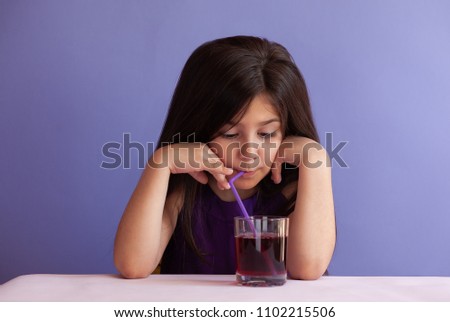 Cute little brunette girl drinking fresh cherry juice