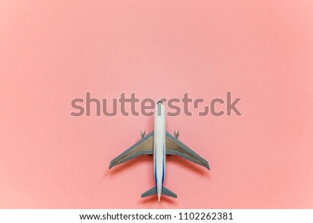 Simply flat lay design with miniature toy model plane pink pastel colorful trendy paper background. Travel by plane vacation summer weekend sea adventure trip concept