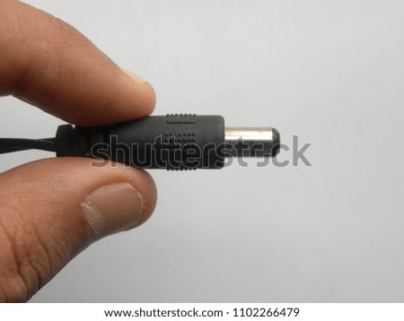 Hand of man holding black color male jack of power plug adapter on white background