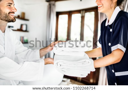 Housekeeper handing over fresh towels Royalty-Free Stock Photo #1102268714