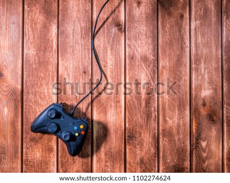 one black modern video game gamepad on the wooden background