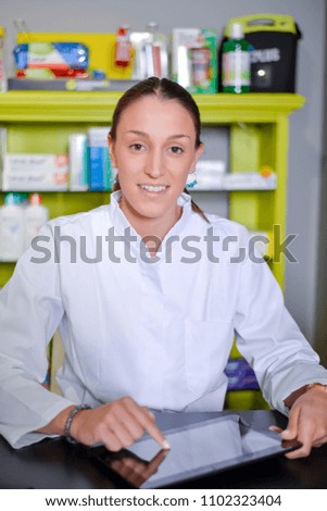 Smiling happy confident young woman pharmacist working on a desk in the pharmacy