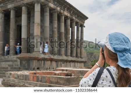 Female tourist taking a picture of the ancient famous temple Garni in Armenia                              