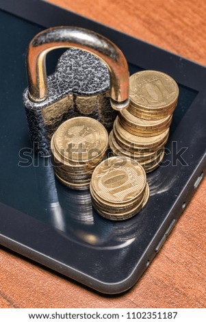 Padlock and gold coins on a Tablet PC. Data security concept
