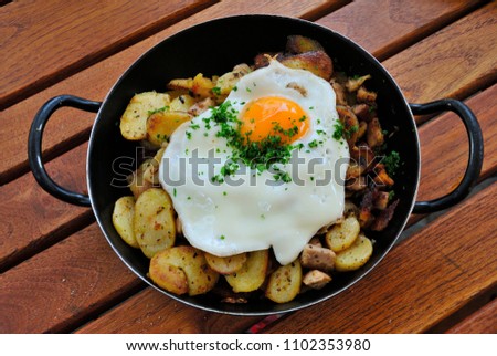 Tyrolean kedgeree of fried meat and potatoes served with fried egg Royalty-Free Stock Photo #1102353980