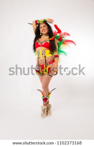Very fit young hispanic woman in Carnaval costume and athletic shoes posing on clean white background