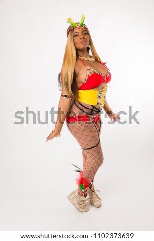 Fit young black woman in Carnaval costume and athletic shoes posing on clean white background