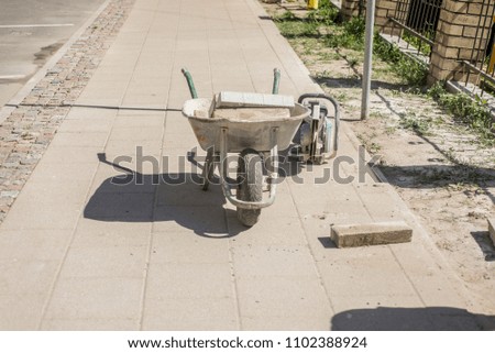 wheelbarrow on a sidewalk, distant photo.