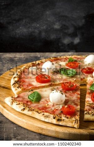 Italian pizza slice with tomatoes, cheese and basil on wooden table. 