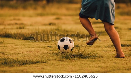 An action picture of a group of kid playing soccer football for exercise in community rural area under the sunset. Picture with copy space.