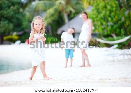 Cute little girl portrait at beach with her family on background