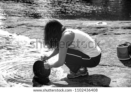 After Lunch Camping Chore: Lady washing cooking utensils in Black and White