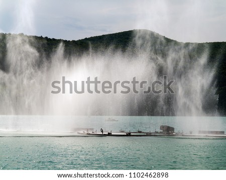 Beautiful authentic landscape of the mountain lake Abrau with a fountain in the center on a sunny day. Krasnodar Region, Russia