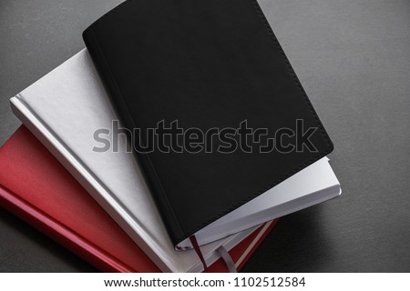 Office dark table. Mock up book blank black, red, white, leather cover for magazine, booklet, brochure, diary, business portfolio mock-up design template on black  background. Flat lay, top view, copy
