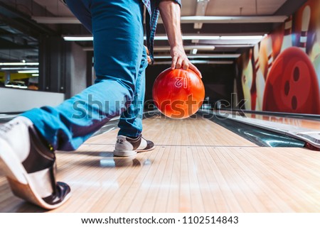Man throwing ball in bowling alley. View from behind