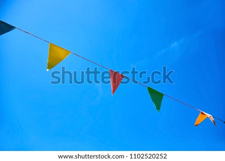 Multicolored triangular paper festival flags on blue sky background. Outdoor Celebration Party. Festive mood.