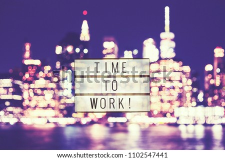 Time to work text in a lightbox, blurred Manhattan city lights in background, color toned picture.