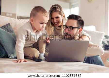 Smiling young parents and focused son using laptop at home.