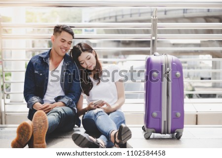 Handsome boyfriend and beautiful girlfriend take a rest and listening music together. Traveler couple get honeymoon at foreign country. They look romantic and sweet. They wear jeans. city background